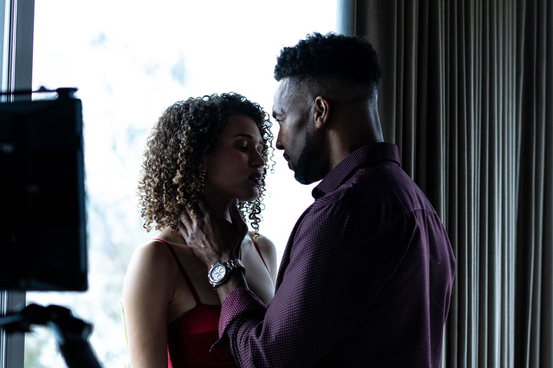 Samantha Neyland Trumbo in a still frame from movie Sinister Surgeon with actor Anthony Montgomery. The actors are in an intense embrace with pained expressions.